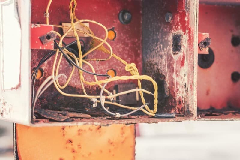 Câblage électrique vétuste et désordonné dans un ancien boîtier métallique