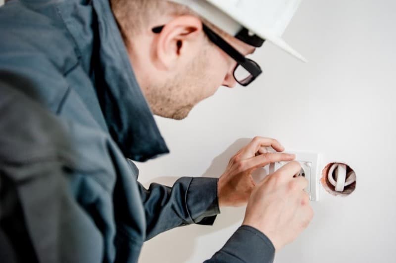 Électricien posant une prise murale dans une habitation