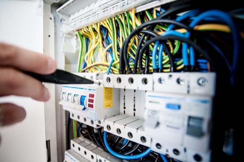 Électricien vérifiant les disjoncteurs d'un tableau électrique modulaire
